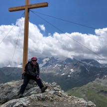 Marion on the summit of 3033 meters high Piz Umbrail with Ortler in clouds